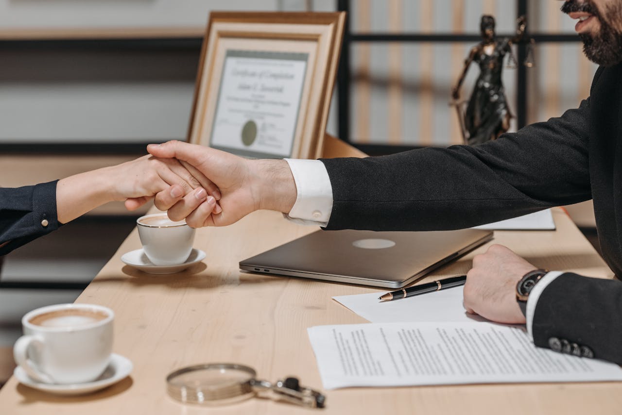 A formal handshake over a business contract in a corporate office setting.