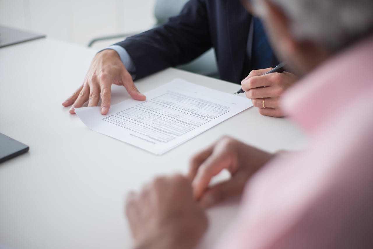 Two professionals engaging in a business meeting, signing documents for a consulting agreement.